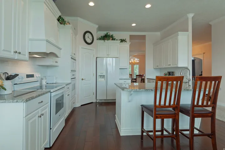 White cabinetry, granite countertops, subway tile backsplash, dark wood-finish flooring, and recessed lighting