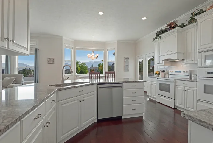 Kitchen featuring white cabinetry, light-toned countertops, wood-finish flooring, and integrated stainless steel appliances