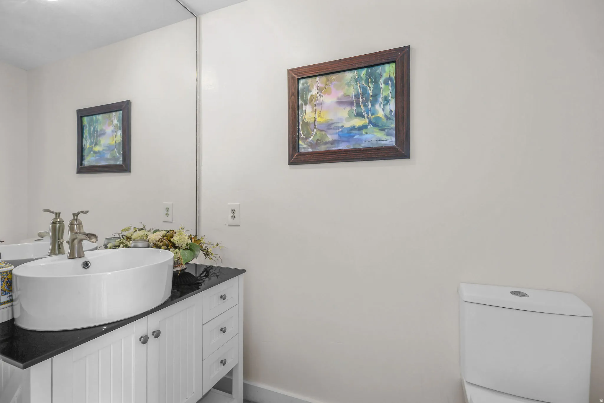 Integrated mirror, vessel sink, vanity with cabinet storage, solid surface countertop, and modern toilet