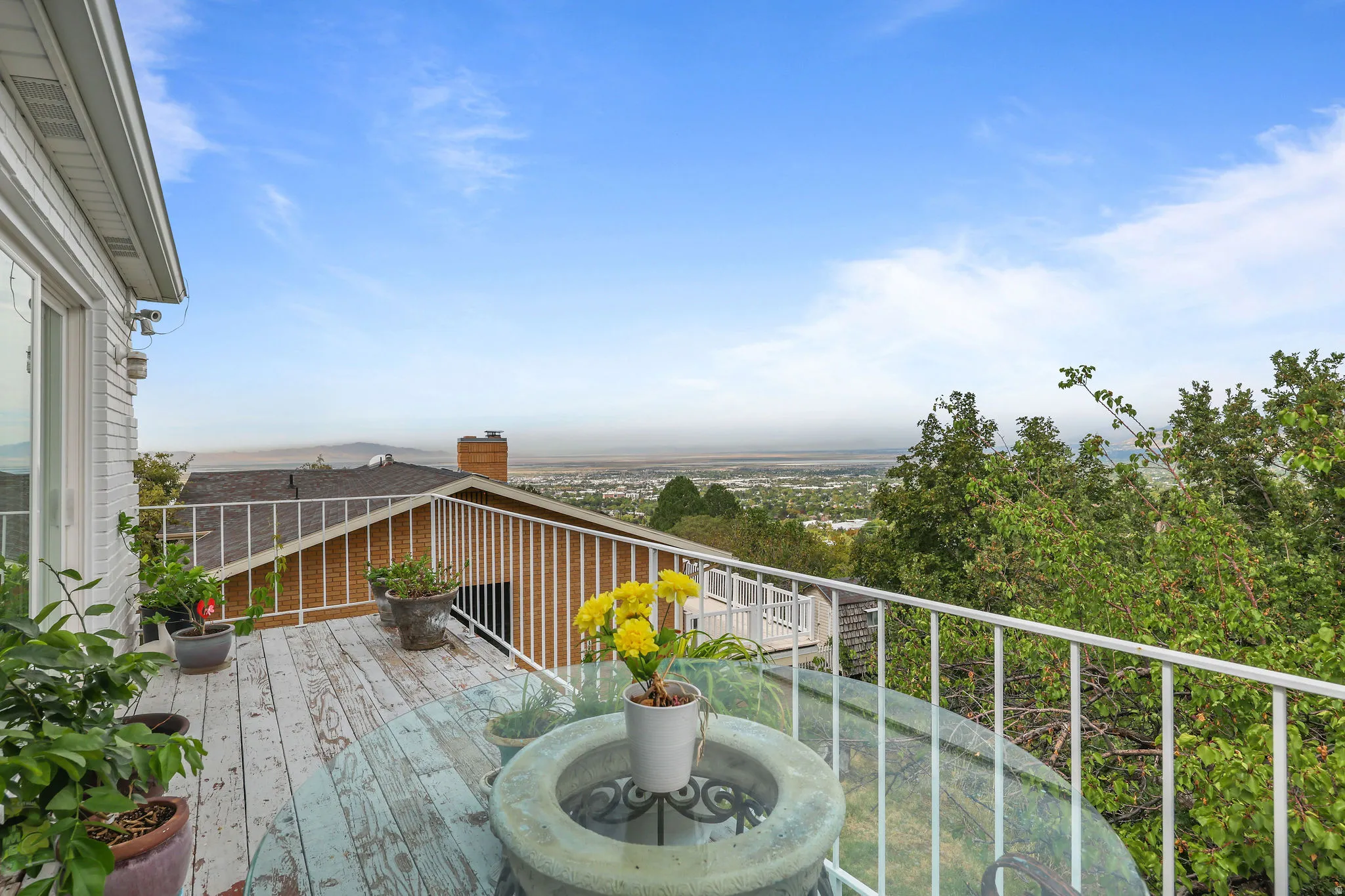 Elevated deck with white metal railing, wood-finish flooring, and expansive distant scenery