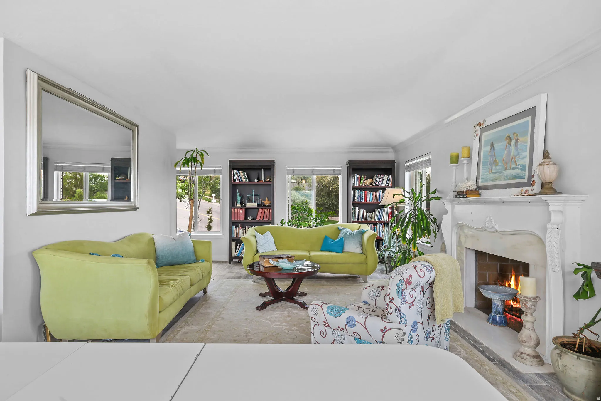 Living area featuring a detailed fireplace, built-in shelving, multiple windows, and crown molding