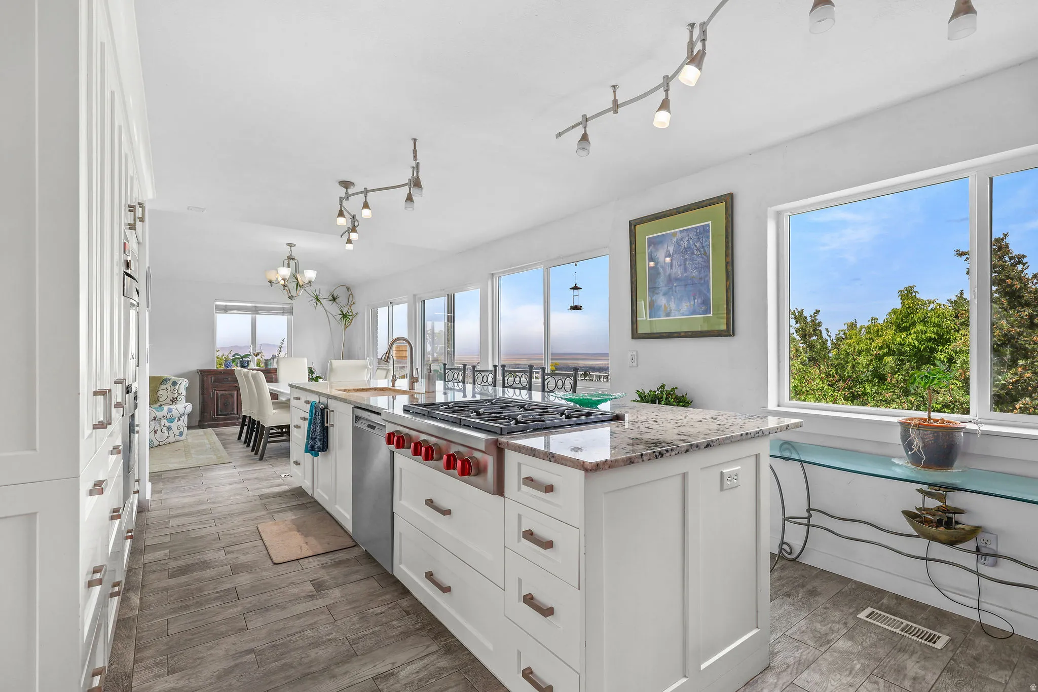 Kitchen featuring a central island with a built-in range, white cabinetry, granite countertops, and wood-finish flooring