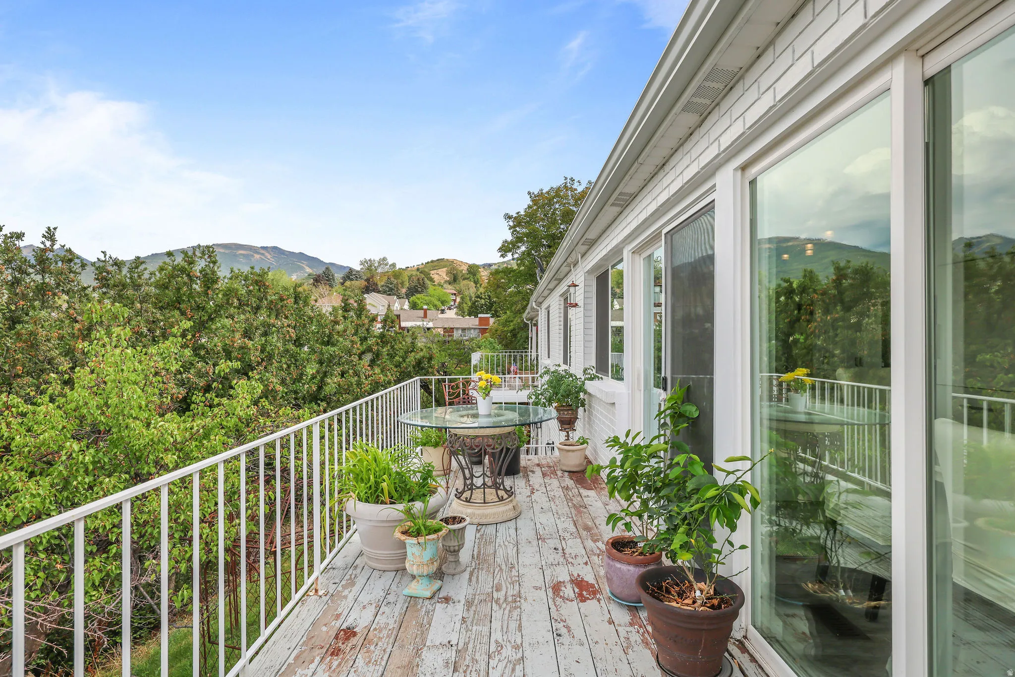 Expansive outdoor deck with a white metal railing, multiple large windows, and sliding glass doors