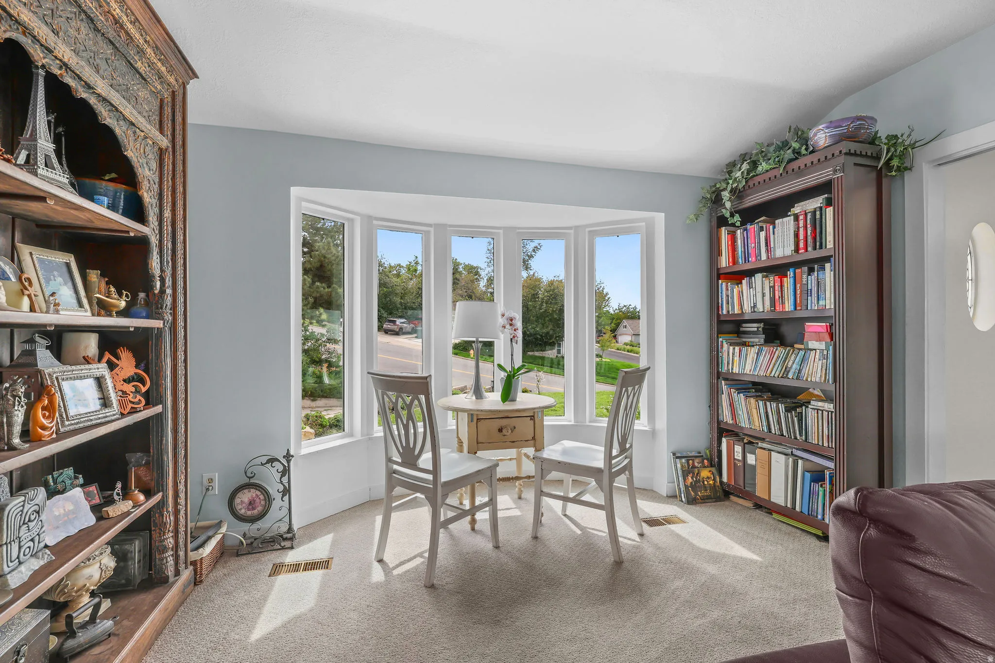 Bay window with multiple panes, light blue wall paint, and carpeted flooring