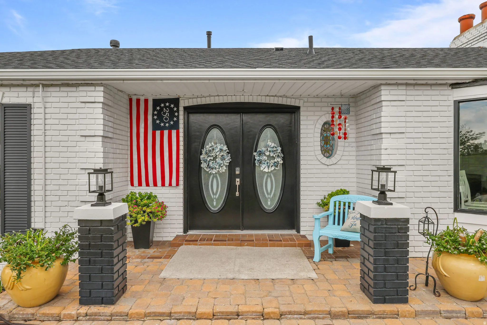 White painted brick exterior with black shutters and a black double entry door featuring oval glass inserts