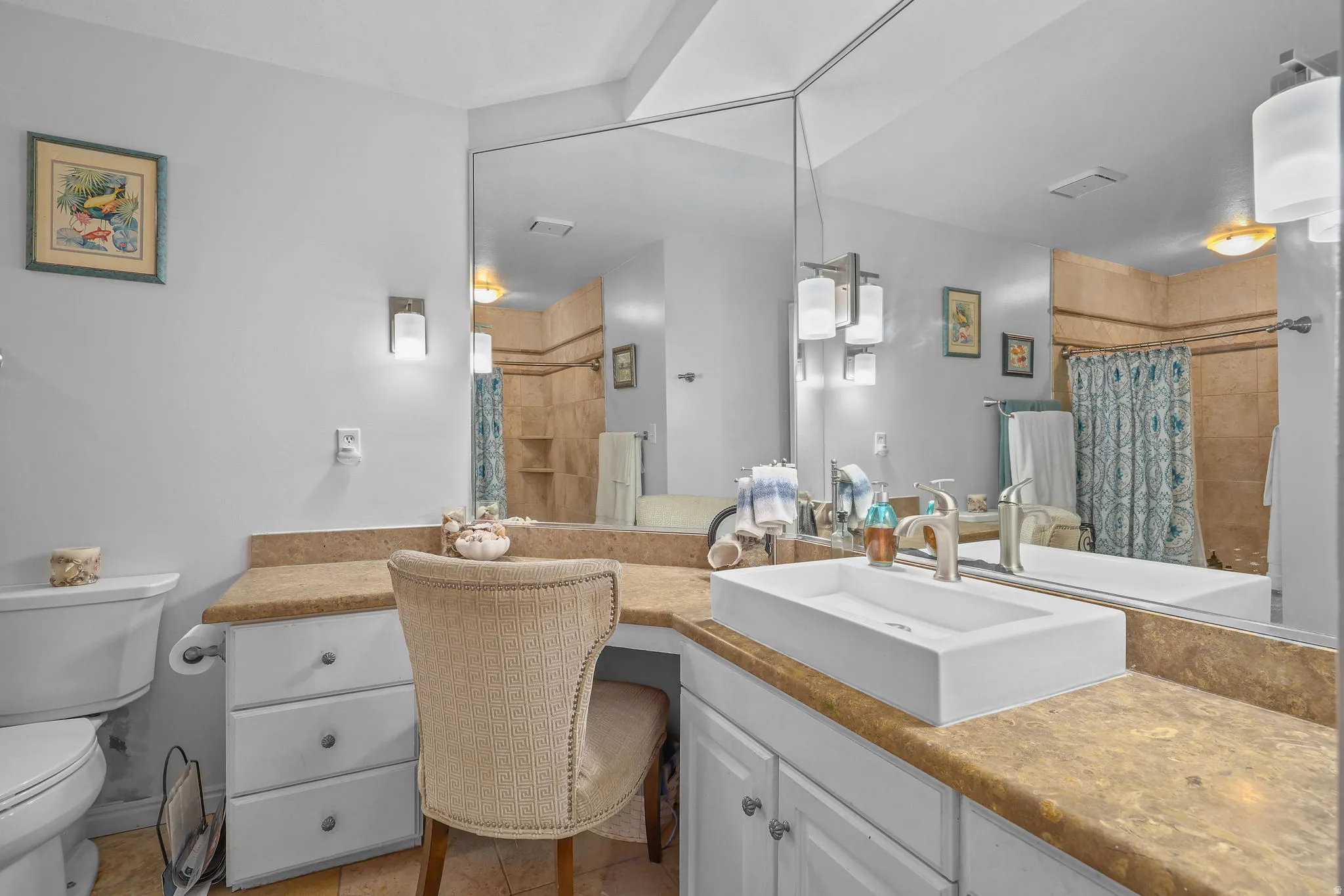 Vanity area featuring a vessel sink, extensive countertop space, integrated cabinetry, and an oversized wall mirror