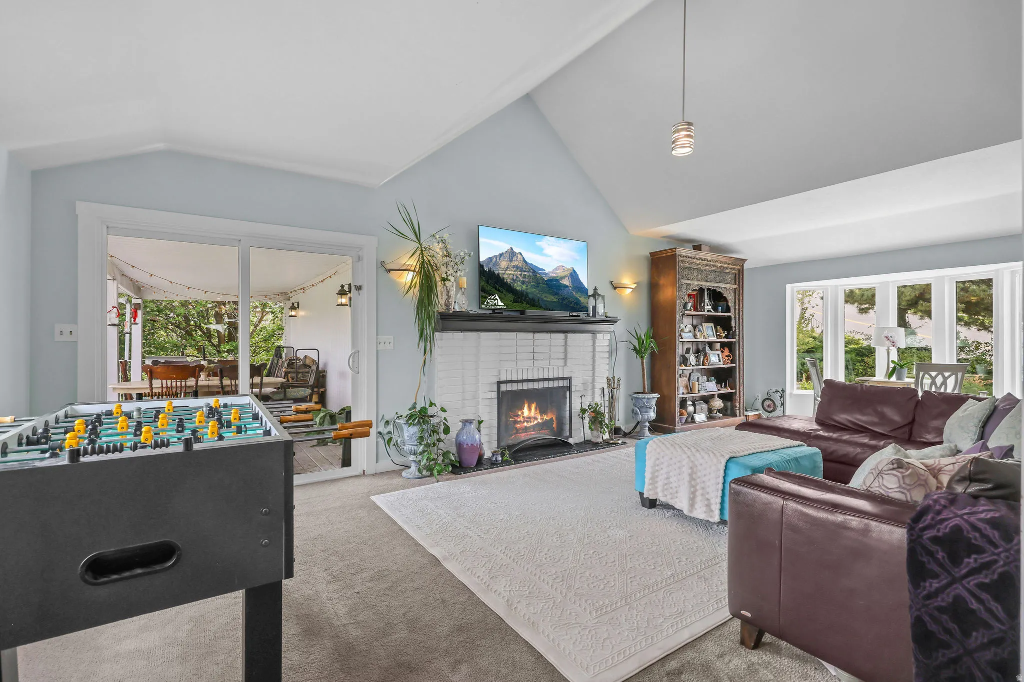 Vaulted ceiling living area with a white brick fireplace, gas insert, and built-in mantle