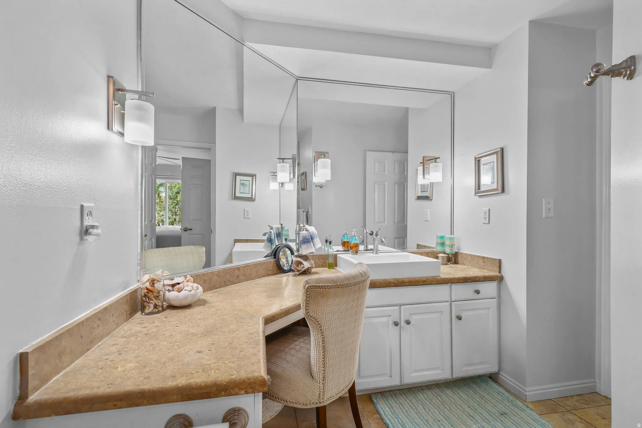 Vanity area featuring an integrated sink, ample counter space, custom cabinetry, and large wall-mounted mirrors