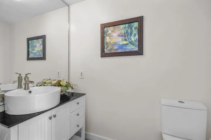 Integrated mirror, vessel sink, vanity with cabinet storage, solid surface countertop, and modern toilet