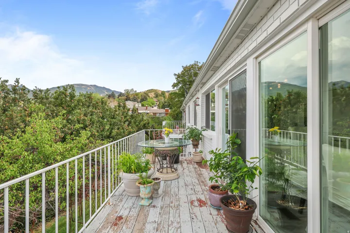 Expansive outdoor deck with a white metal railing, multiple large windows, and sliding glass doors