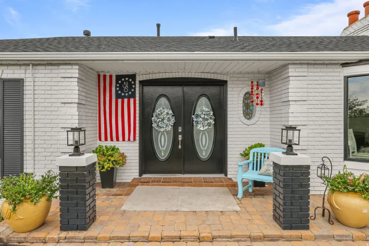 White painted brick exterior with black shutters and a black double entry door featuring oval glass inserts