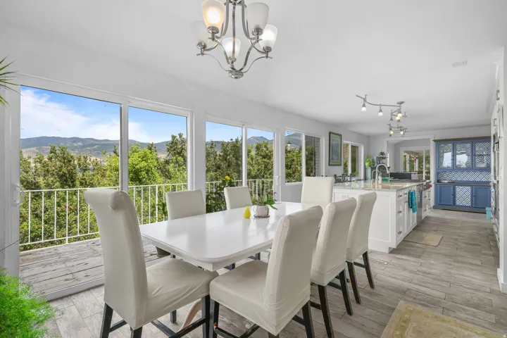 Open-concept living area with large glass sliding doors, wood-finish flooring, a contemporary chandelier, a kitchen island with built-in cabinetry, and a distinct blue built-in hutch