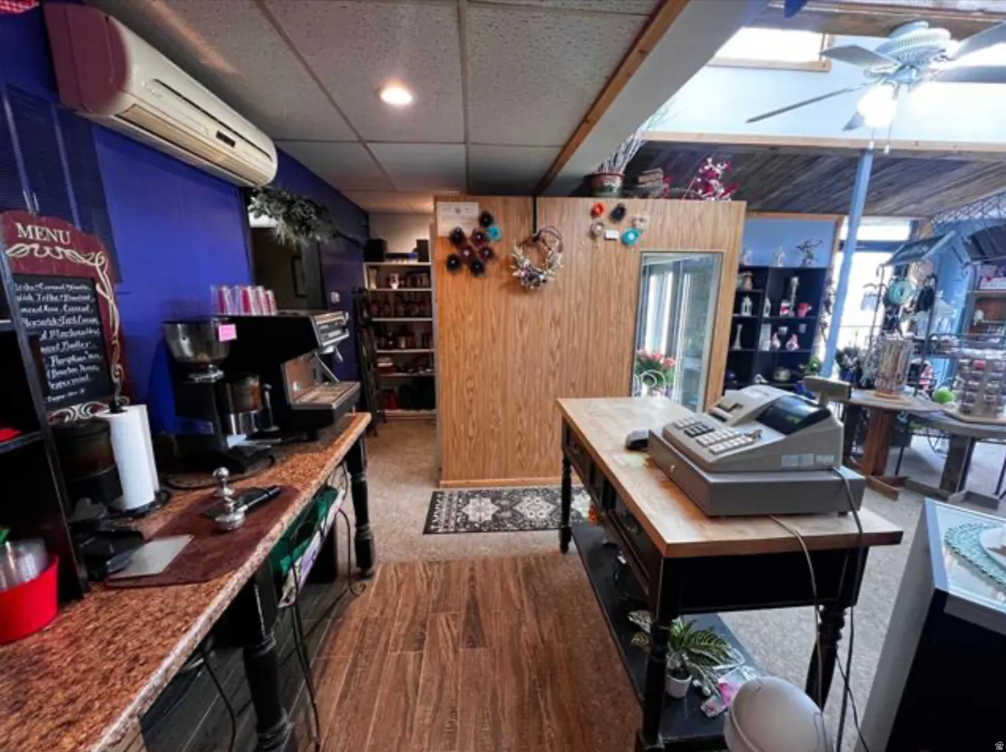 Wood-finish flooring, drop ceiling with recessed lighting, skylight feature, wall-mounted air conditioning unit, and built-in shelving