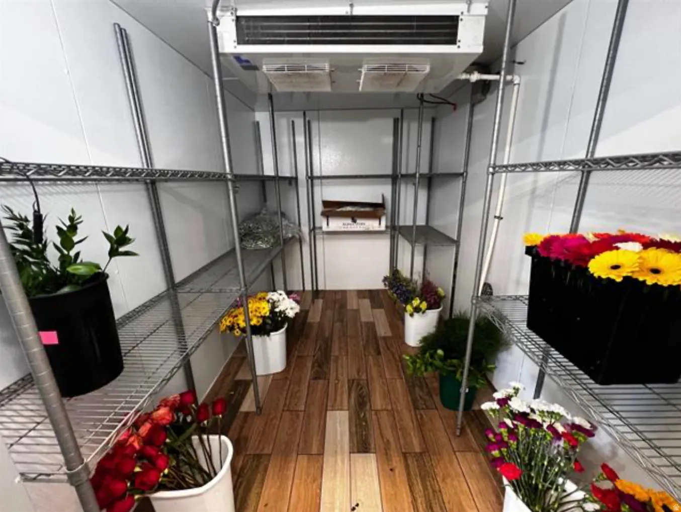 Wood-finish flooring, white panel walls, and extensive metal shelving