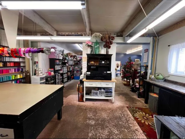 Exposed ceiling beams, recessed lighting, and a window with white curtains