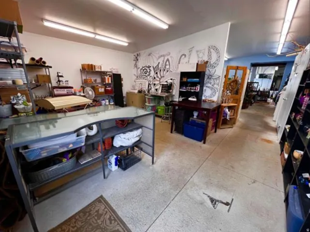Concrete flooring, white walls, exposed fluorescent lighting, built-in shelving, and a wood-finish door frame