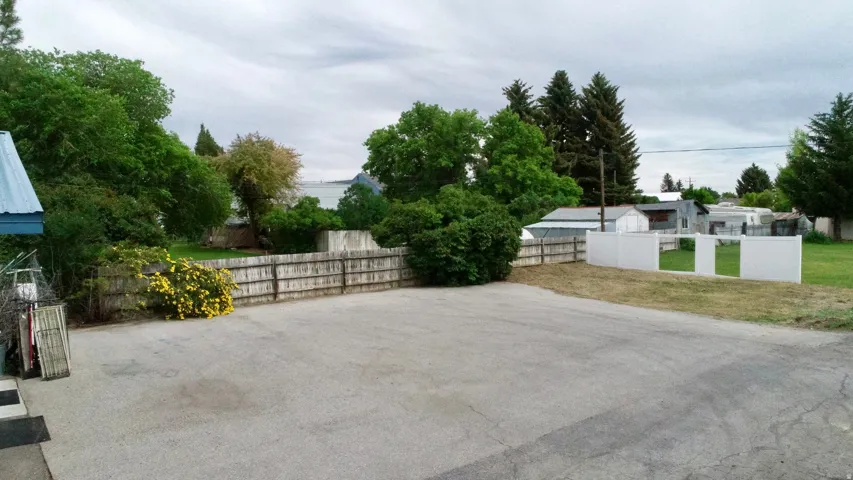 Paved surface, wood fence, white fencing, mature trees, dense foliage