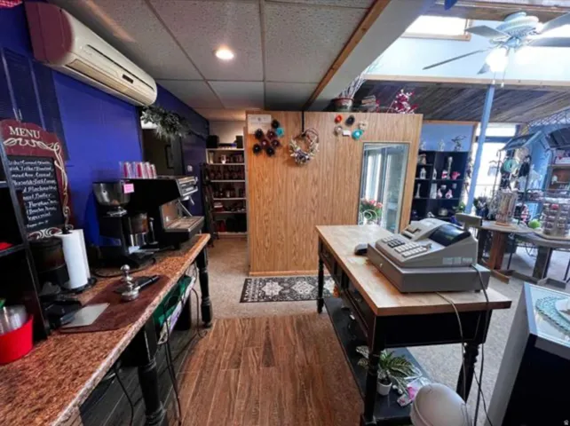 Wood-finish flooring, drop ceiling with recessed lighting, skylight feature, wall-mounted air conditioning unit, and built-in shelving