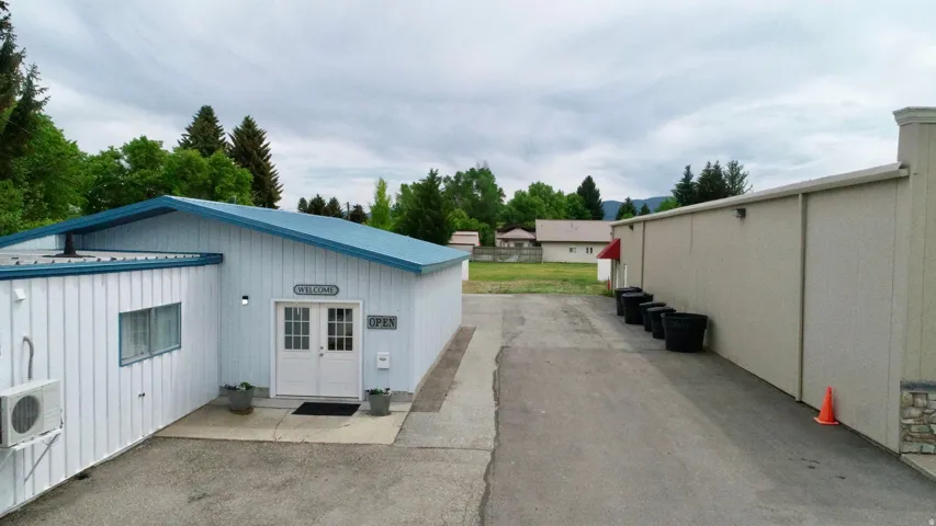 Building exterior featuring vertical siding, a blue metal roof, an air conditioning unit, and a paved lot