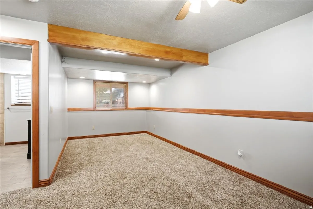 Carpeted room featuring a ceiling fan, recessed lighting, and a wood-trimmed window