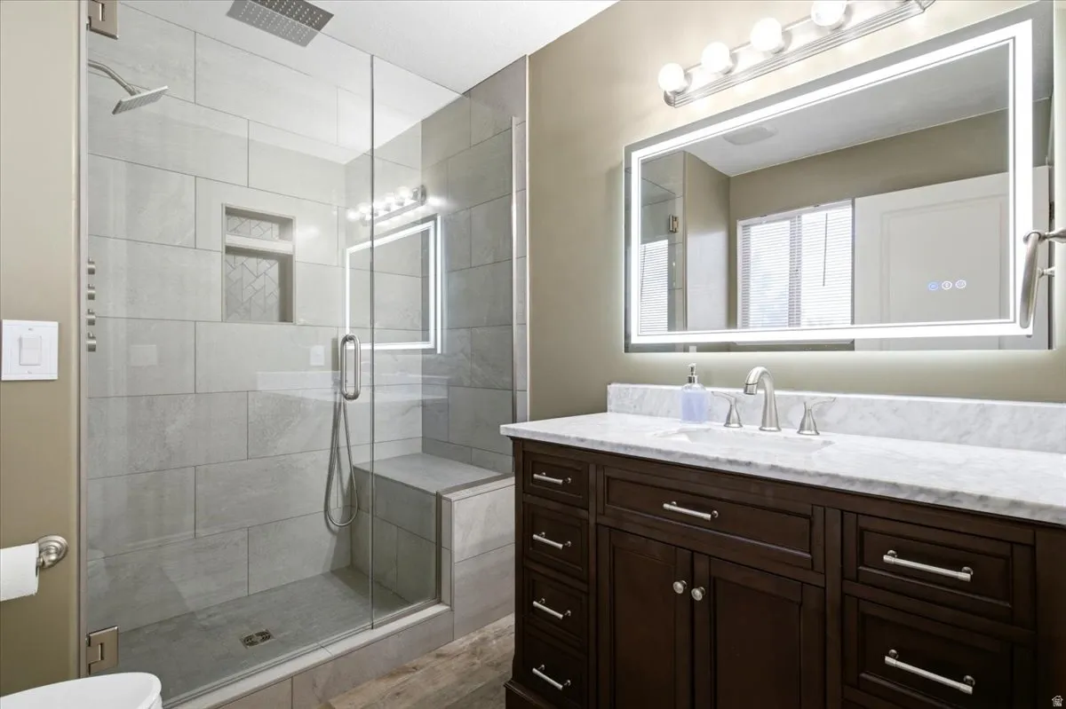 Glass-enclosed shower with a built-in bench, rain shower head, and tile niche