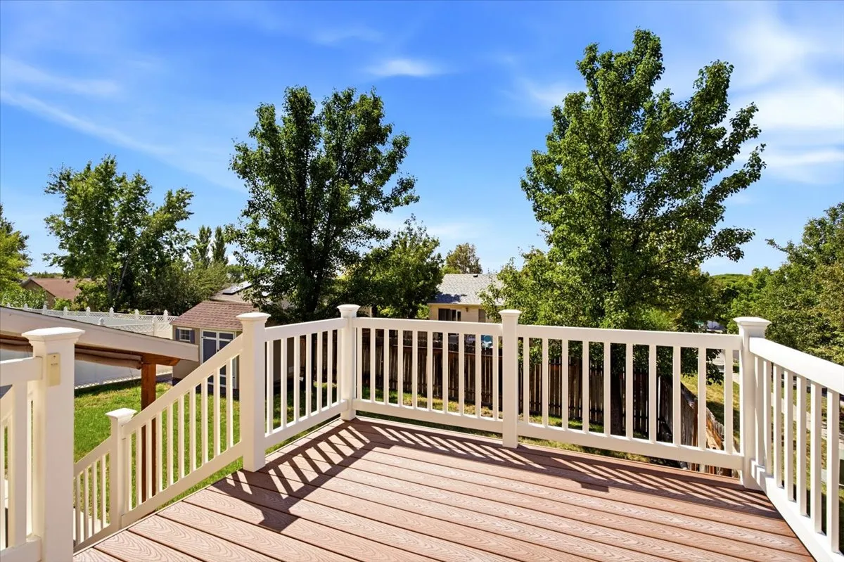 Expansive outdoor deck featuring wood-finish flooring and white railings