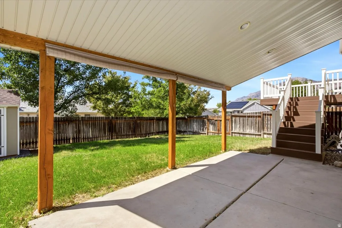 Covered patio with a concrete surface, supported by wood posts, and a wood privacy fence