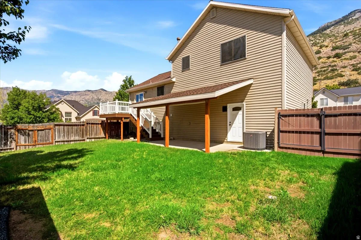 Expansive backyard featuring a manicured lawn, wood fencing, and a covered patio