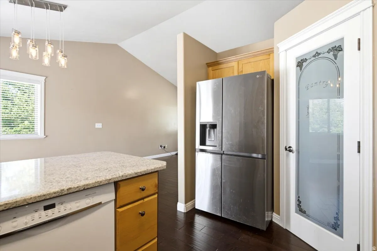 Kitchen island with a light-toned countertop, wood-finish cabinetry, and a built-in dishwasher
