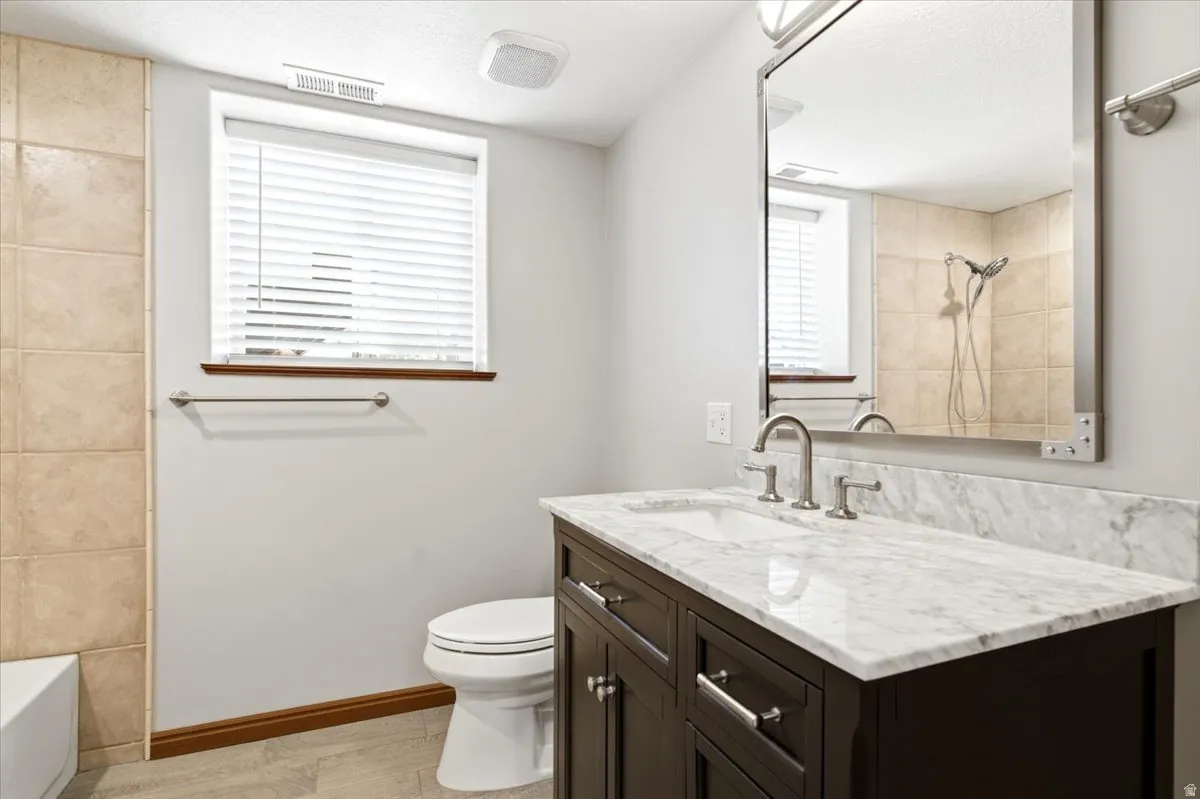 Vanity with a light-colored stone countertop, undermount sink, and brushed nickel fixtures