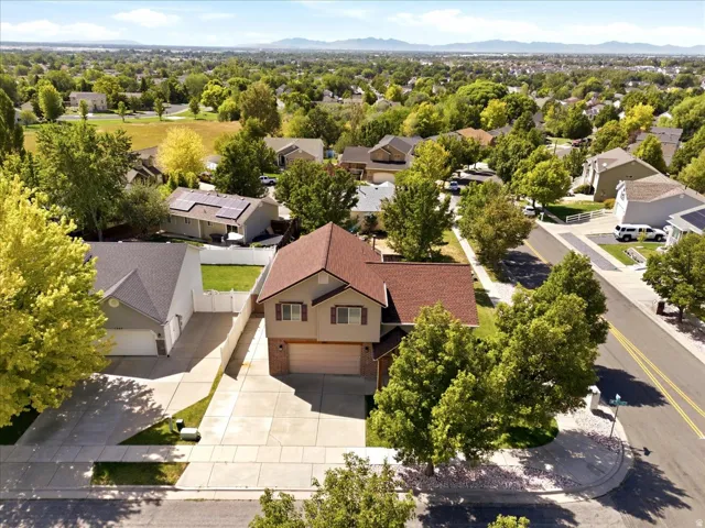 Two-story residence with a brown shingle roof, two-car garage, and mature landscaping