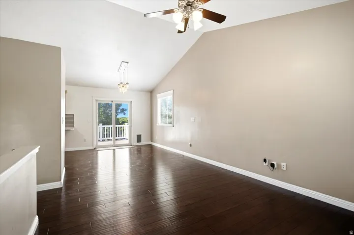 Vaulted ceiling with a ceiling fan, recessed lighting, wood-finish flooring, and white trim