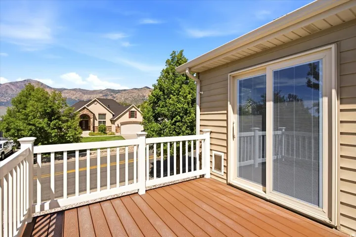 Deck with wood-finish flooring, white railing, and sliding glass door