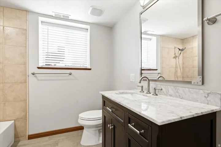 Vanity with a light-colored stone countertop, undermount sink, and brushed nickel fixtures