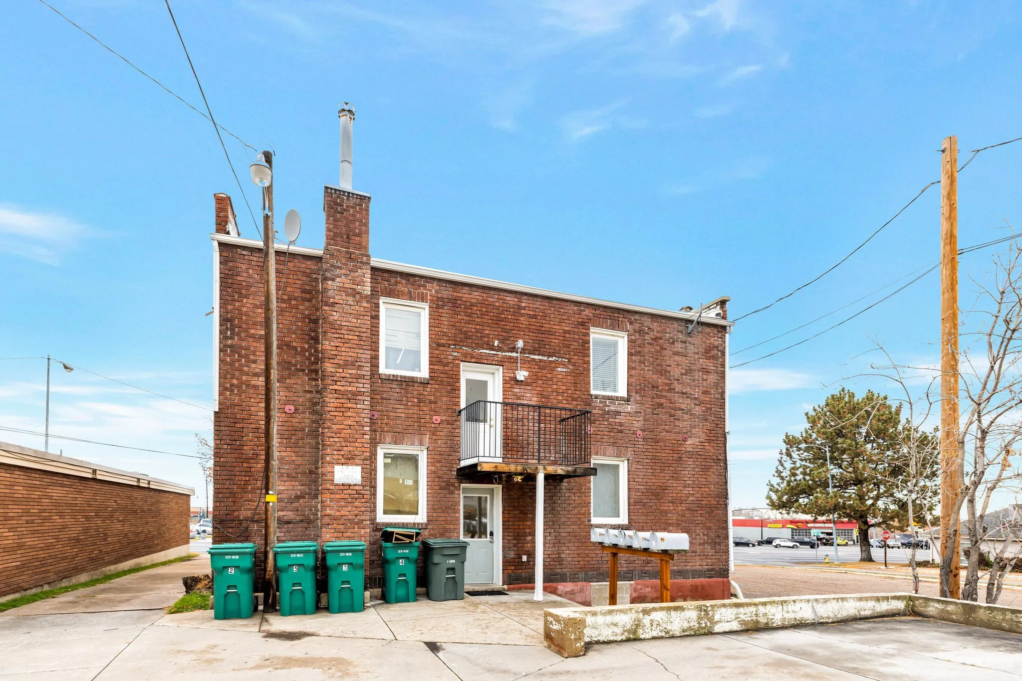 Brick exterior with a metal balcony, multiple windows, and exterior lighting