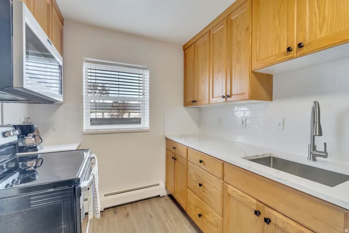 Kitchen featuring wood cabinetry, white subway tile backsplash, white countertops, and wood-finish flooring