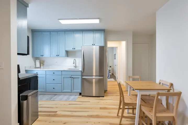 Full kitchen featuring light blue cabinetry, white countertops, stainless steel appliances, and wood-finish flooring