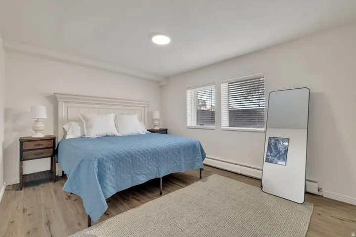 White walls with recessed ceiling lighting, wood-finish flooring, two large windows, and a white paneled headboard