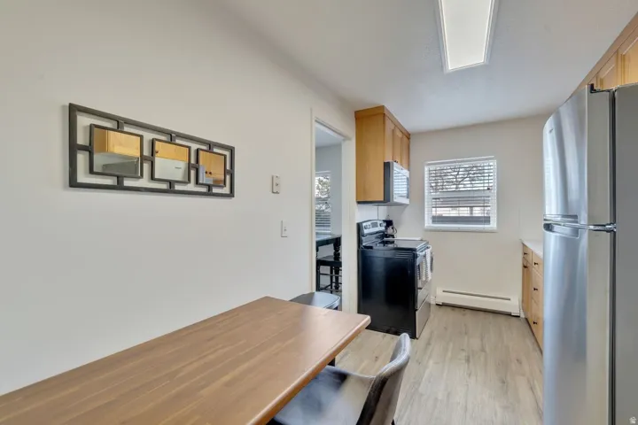 Kitchen featuring stainless steel appliances, wood-finish cabinetry, and wood-finish flooring
