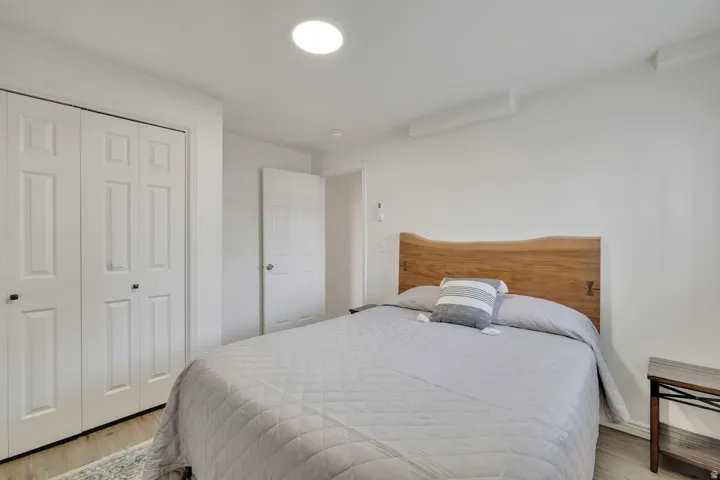Recessed ceiling lighting, wood-finish flooring, paneled bifold closet doors, and white walls