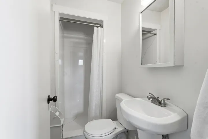 Pedestal sink, wall-mounted medicine cabinet, and a shower fixture