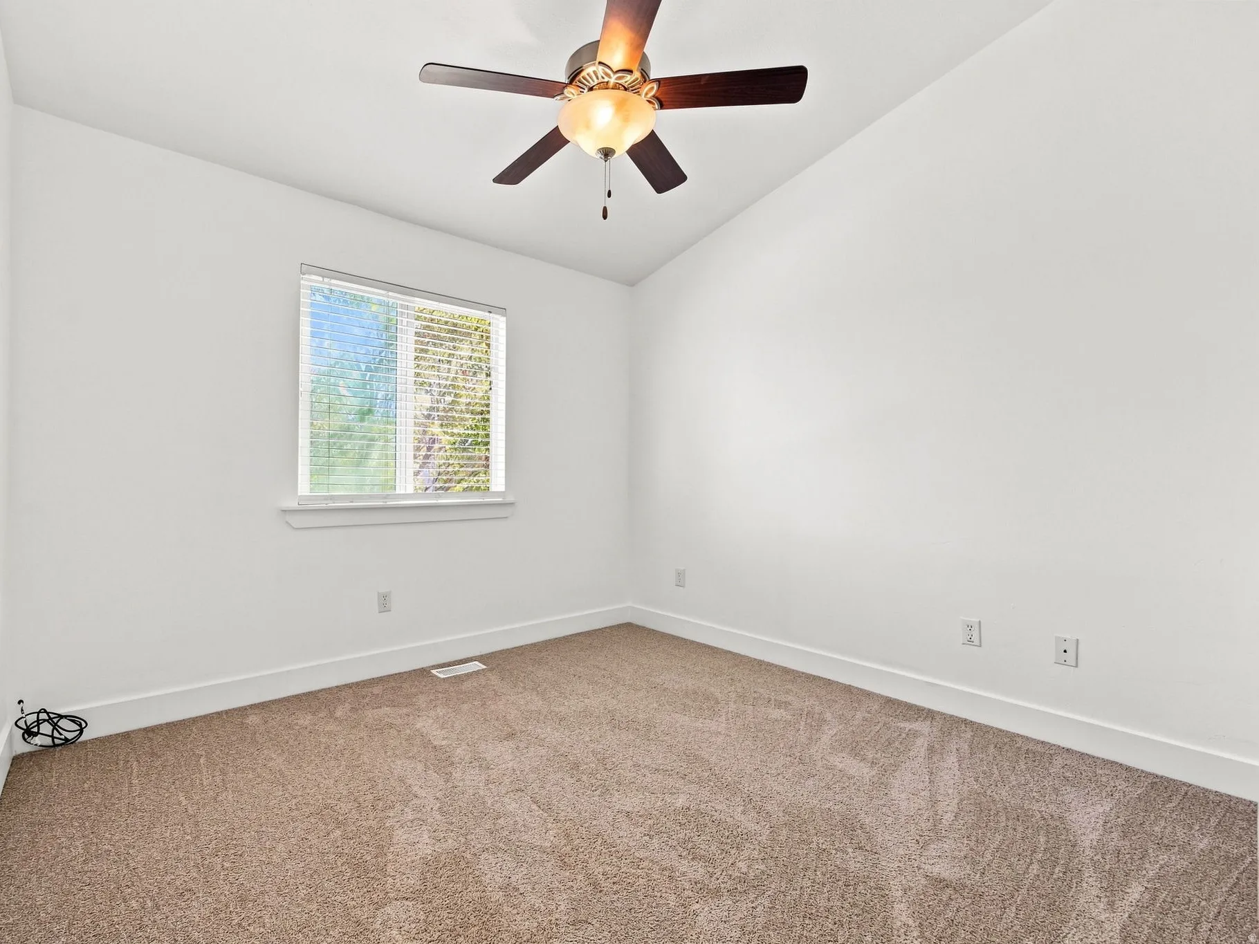 Carpeted flooring, vaulted ceiling, ceiling fan with integrated lighting, window with blinds, and white trim
