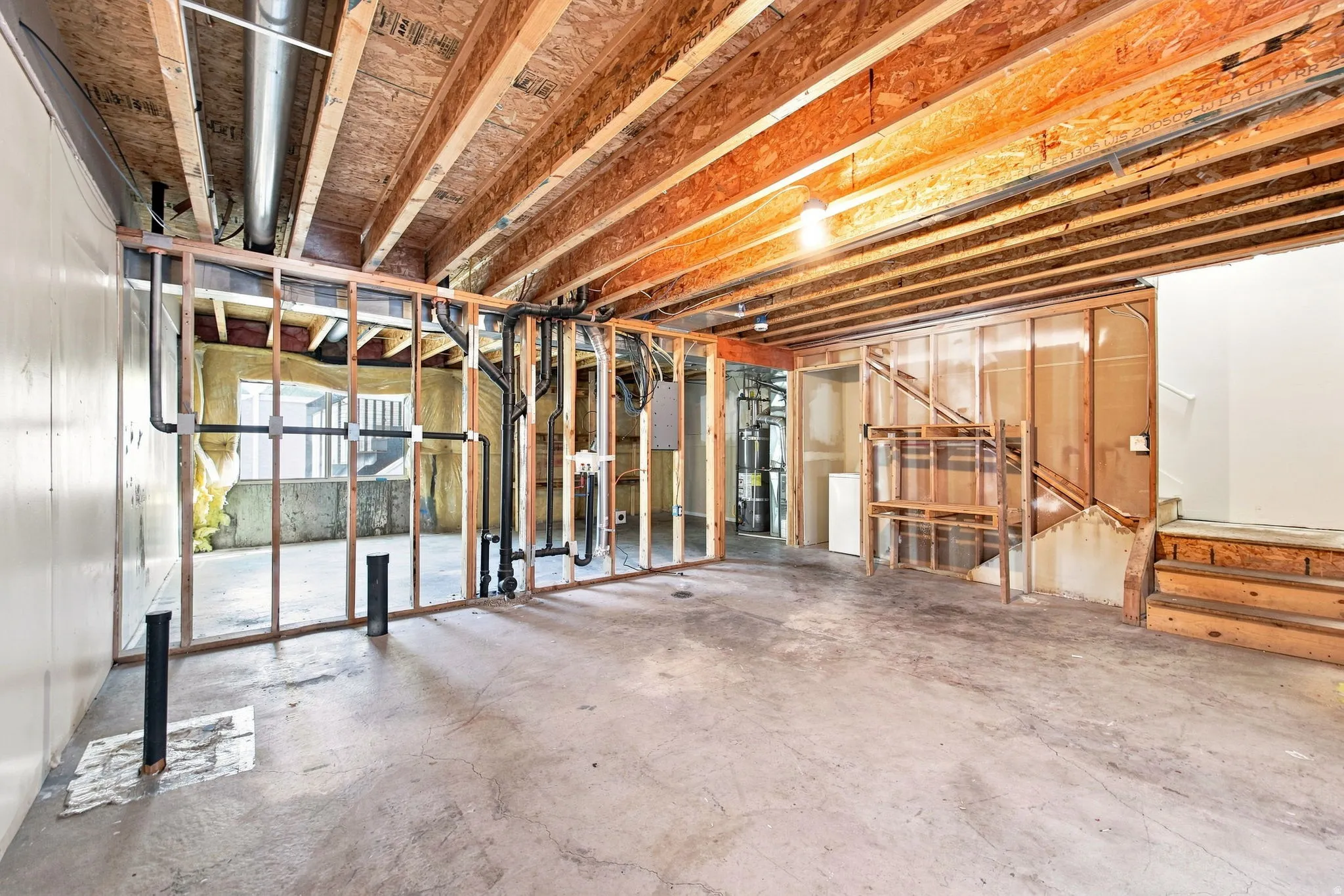 Unfinished basement featuring exposed wood joists, concrete flooring, and partial wall framing