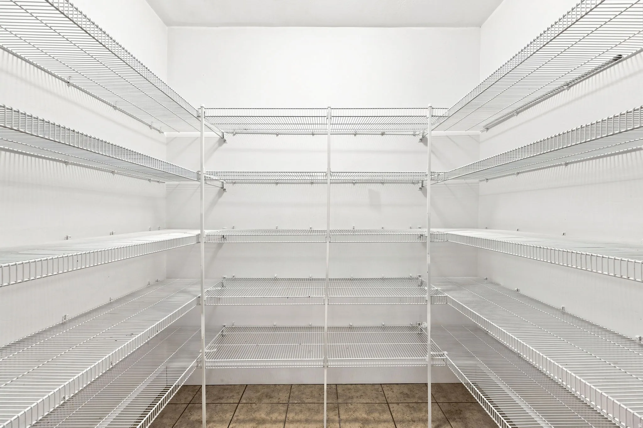 Expansive pantry featuring multi-level wire shelving, white walls, and tiled flooring