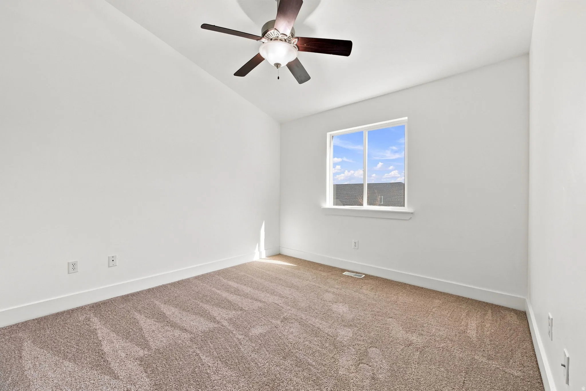 Neutral-toned carpeting, white walls, recessed window, and a ceiling fan with integrated lighting