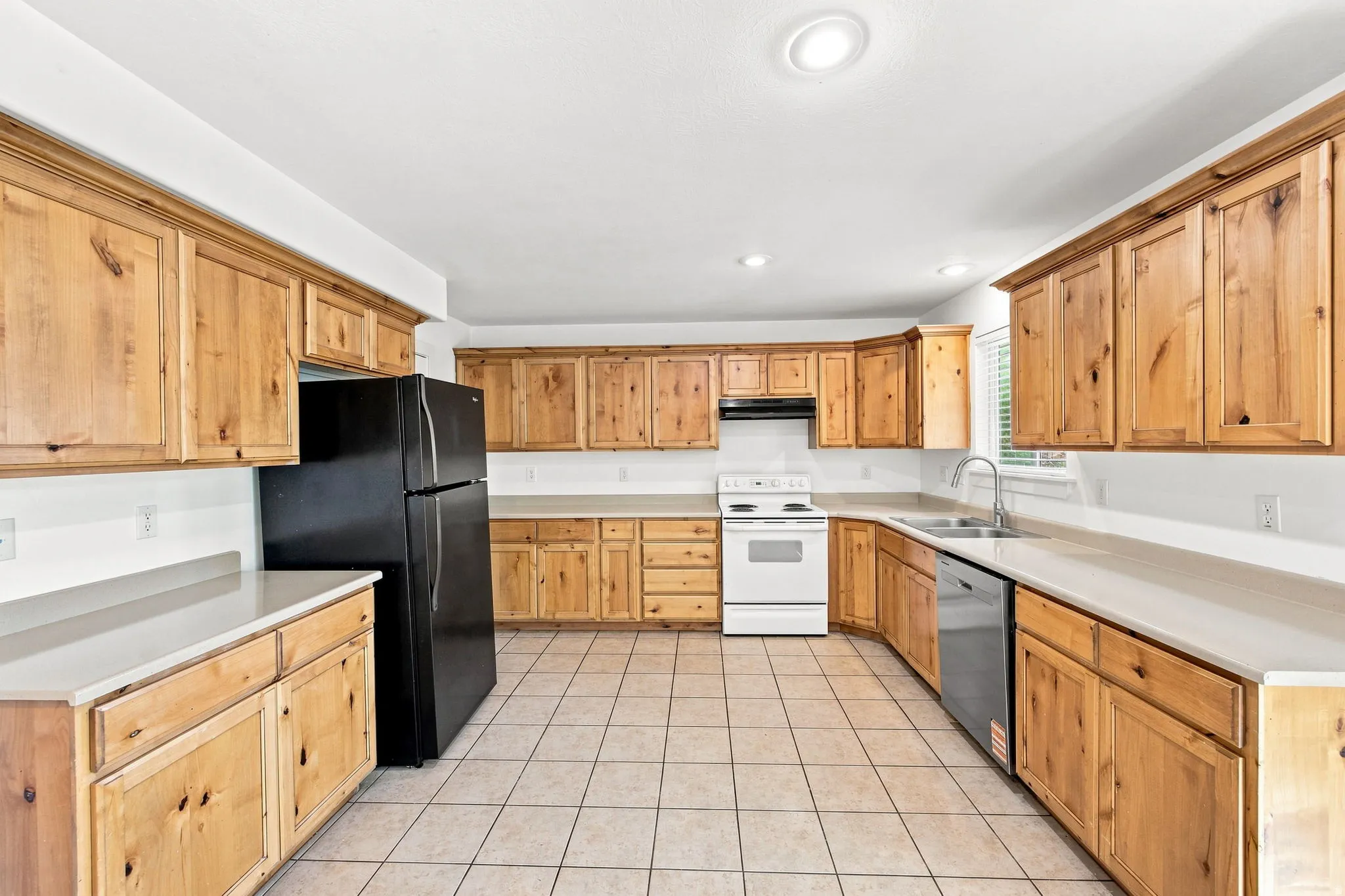 Kitchen featuring extensive wood-finish cabinetry, light-toned countertops, tile flooring, and recessed lighting