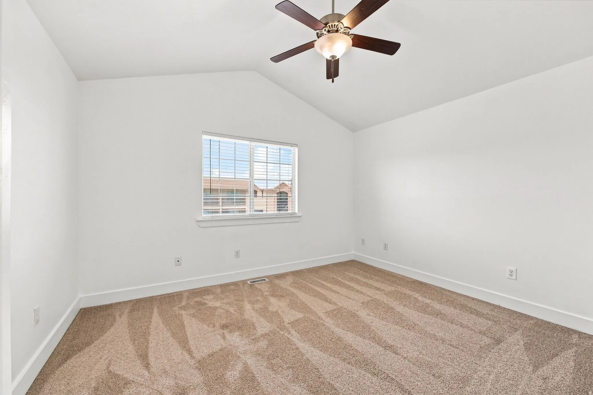 Vaulted ceiling with a ceiling fan, neutral carpet flooring, white walls, and a window with blinds