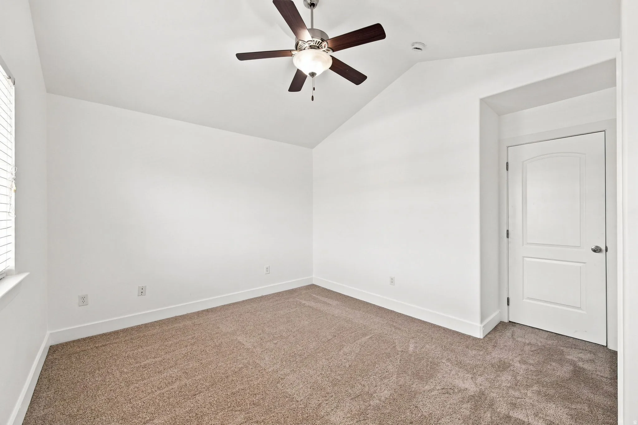 Vaulted ceiling with a ceiling fan, neutral carpet flooring, white walls, and a window with blinds