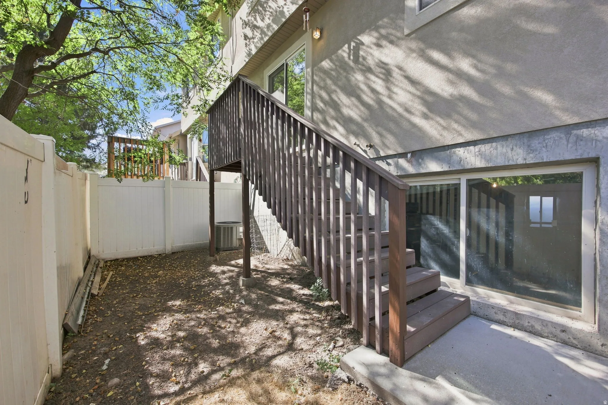 Expansive outdoor space featuring a composite wood staircase and landing, a vinyl privacy fence, and a sliding glass door