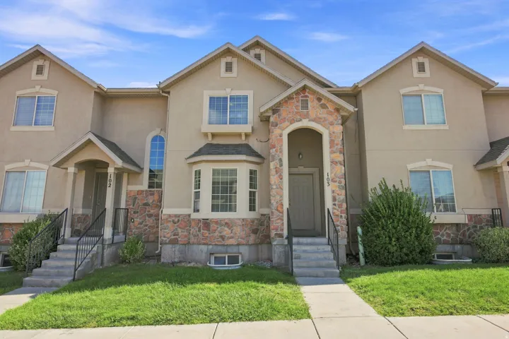 Exterior featuring stucco siding with stone veneer accents, arched entryways, bay windows, and gabled roofs